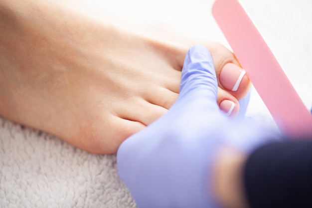 Foto close-upfoto van vrouwelijke voeten bij kuuroordsalon op pedicure procedur. mooie damesvoeten met pedicure in schoonheidssalon. spa manicure