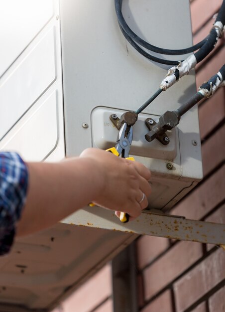 Close-upfoto van werknemer die buizen aansluit op airconditioningsysteem