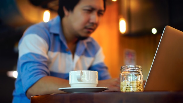 Close-upgeneeskunde en koffiekop over de foto vaag van Aziatische zakenman