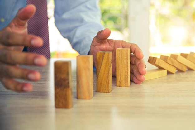 Close-uphand voorkomt dat houten blok geen domino-concepten van financieel risicobeheer en strategische planning en bedrijfsuitdagingsplan valt