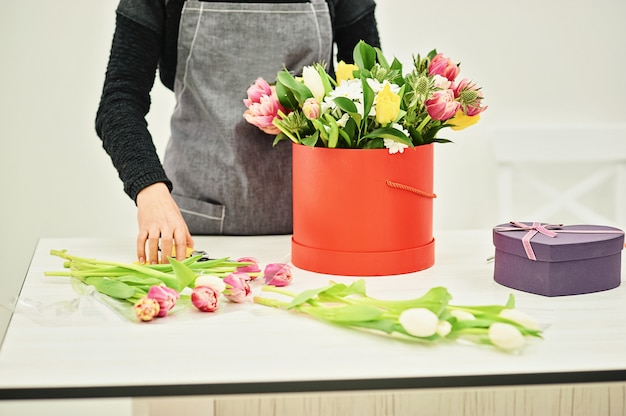 Close-uphanden van bloemist met bloemen. Bloemist bedrijf bloeiende boeket van roze tulpen. Bloemenwinkel concept. Kopieer ruimte
