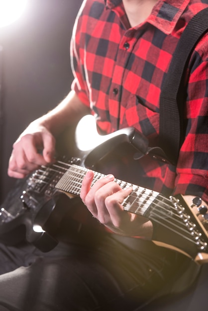 Close-uphanden van jonge gitarist met de elektrische gitaar.