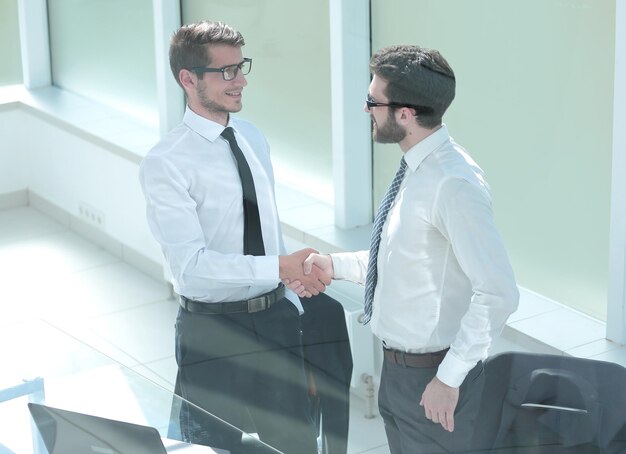 Foto chiudere gli uomini d'affari di stretta di mano in ufficio