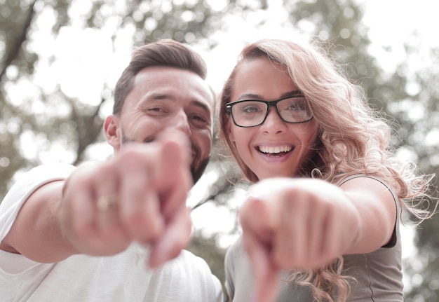 Close uphappy newlyweds standing in the Park and pointing at you