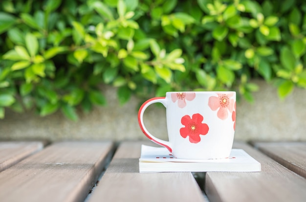 Close-upkop van koffie op wit boek op lijst op de tuinachtergrond