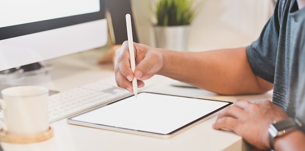 Close-upmening van de jonge mens die tablet op werkplaats gebruiken