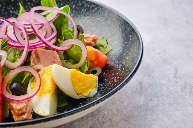 Close-upmening van salade met sla, zalm, tomaat, gekookt ei en ui met olijven