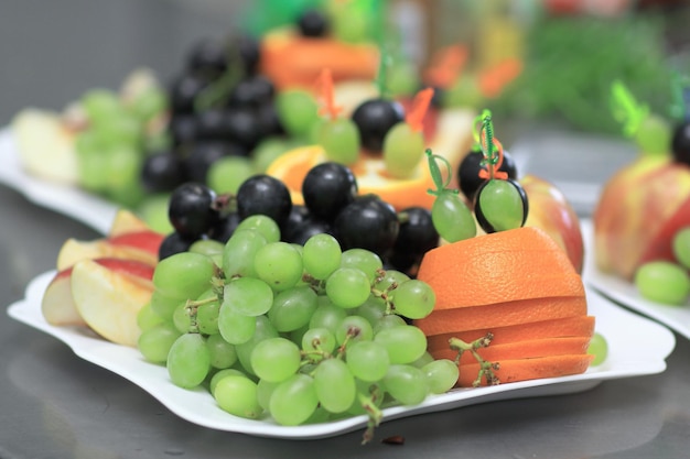 Close upplate with grapes and oranges on blurred background