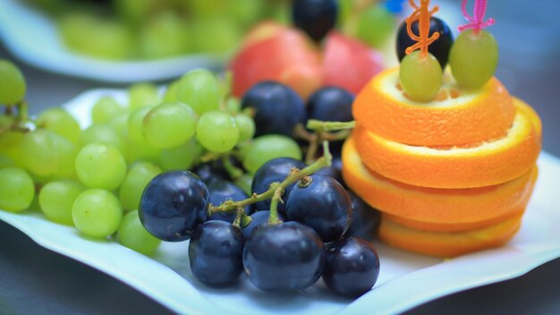 Close upplate with grapes and oranges on blurred background