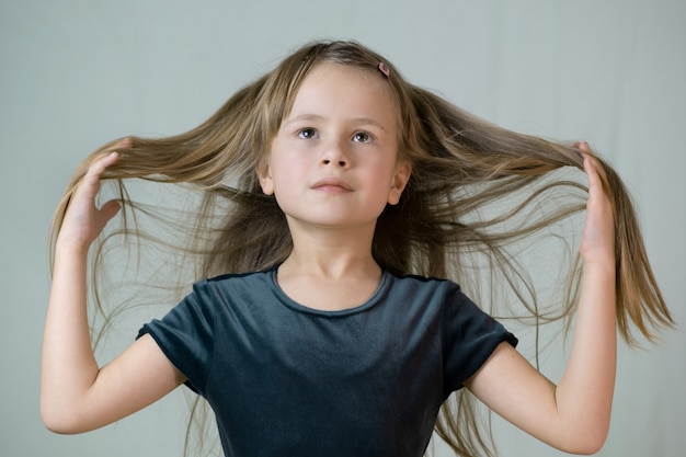 Close-upportret van de gelukkige glimlachende meisjeholding in handen haar lang haar.