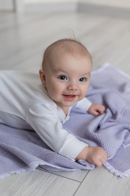 Close-upportret van een schattige pasgeboren baby die op zijn buik ligt op een lila deken op de vloer