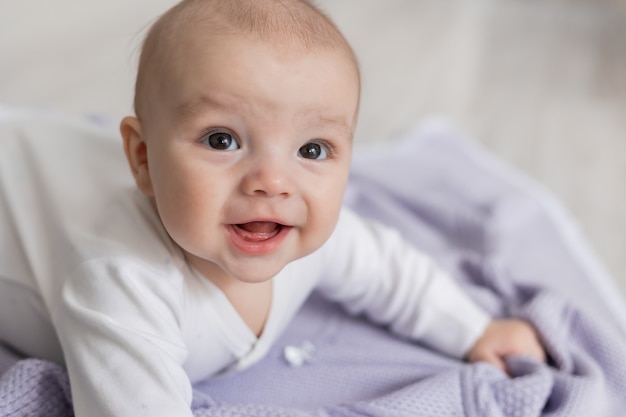 Close-upportret van een schattige pasgeboren baby die op zijn buik ligt op een lila deken op de vloer