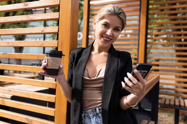 Close-upportret van een succesvolle zakenvrouw van middelbare leeftijd in een stadscafé met een telefoon en een glas