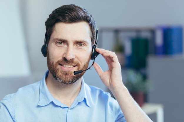 Close-upportret van een zakenman met een headset voor een videogesprek, een man die naar de camera kijkt en een telefoniste glimlacht