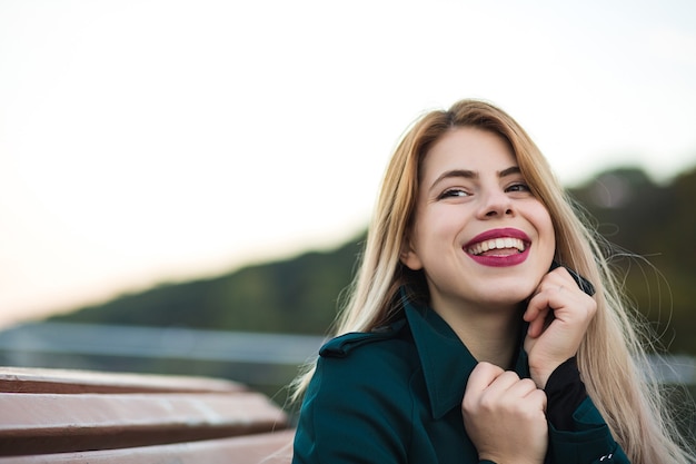 Close-upportret van flirterige blondevrouw die groene laag dragen. Ruimte voor tekst