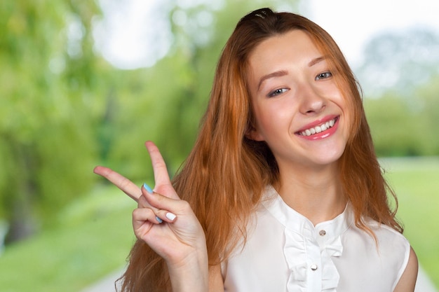 Close-upportret van gelukkige opgewekte succesvolle jonge vrouw die vrede geeft