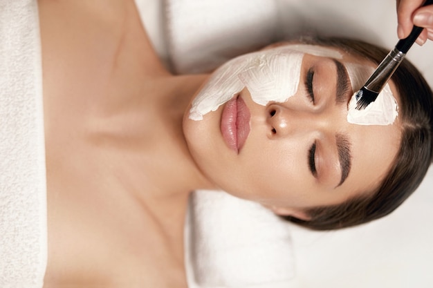 Close-upportret van mooie vrouw met klei gezichtsmasker. Facial of Female behandeling. Cosmetologie. Spa huid- en lichaamsverzorging.