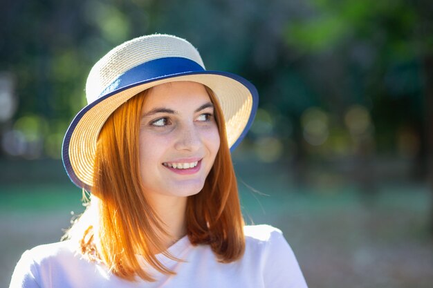 Close-upportret van roodharige hipster tiener die in gele hoed in openlucht in zonnig de zomerpark glimlachen.