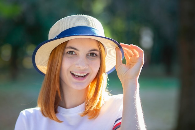 Close-upportret van roodharige hipster tiener die in gele hoed in openlucht in zonnig de zomerpark glimlachen.