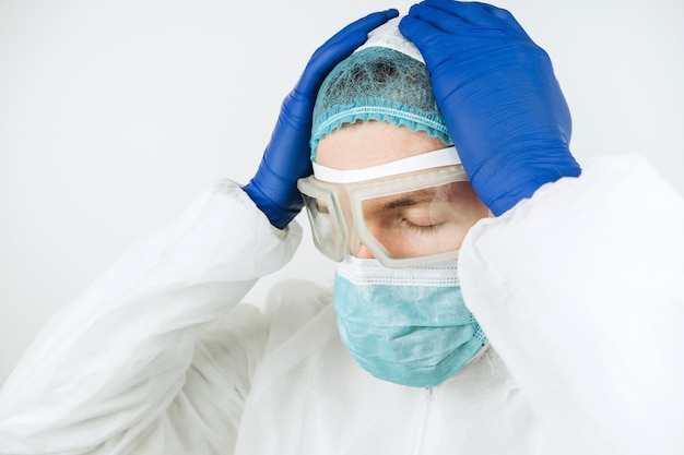 Close-upportret van vermoeide arts na verschuiving in het ziekenhuis. De dokter in beschermende kleding - bril, masker, handschoenen. De arts die patiënten behandelt met coronavirus. Covid-2019