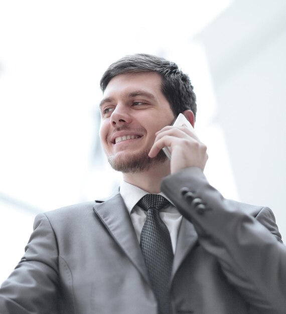 Крупным планом улыбающийся бизнесмен разговаривает по мобильному телефону