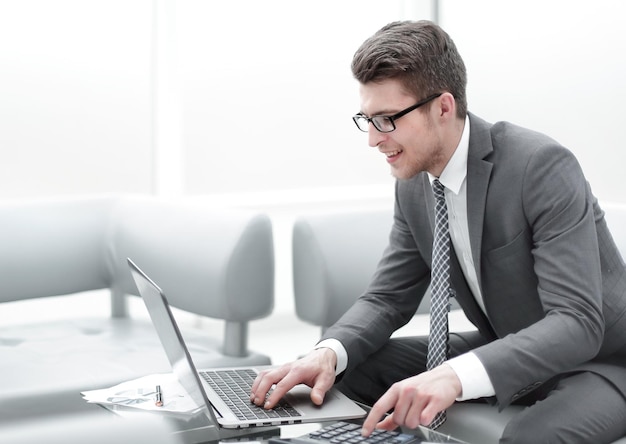 Close upsmiling businessman using laptop and calculator