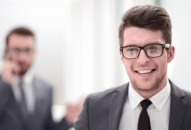 Close upsmiling young businessman in the office background