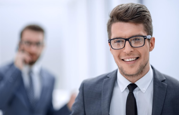 Close upsmiling young businessman in the office background