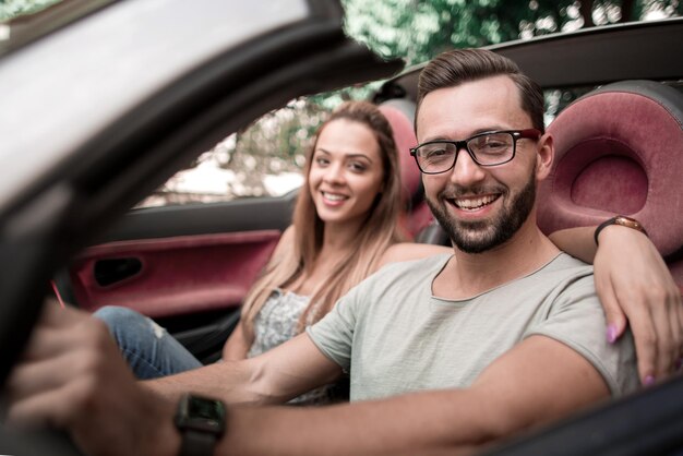 Close upstylish man with his girlfriend traveling in a converti