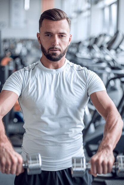 Close upstylish young man working with dumbbells in the gym the concept of a healthy lifestyle