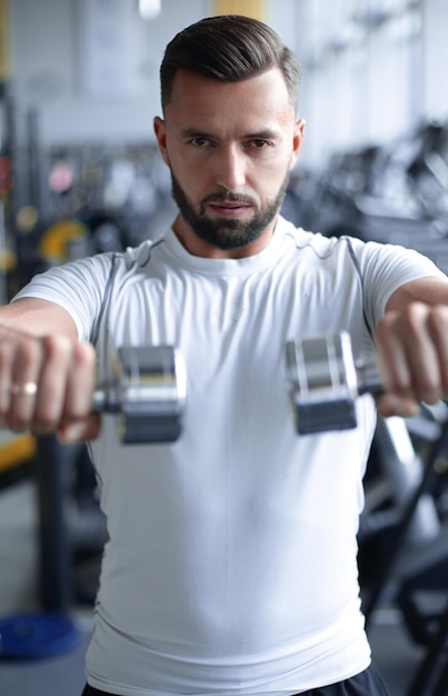 Close upstylish young man working with dumbbells in the gym