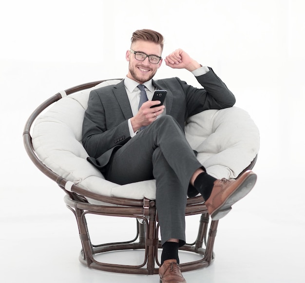 Close upsuccessful businessman with smartphone sitting in a soft chair