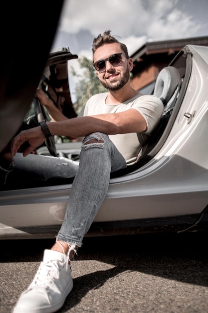 Close upsuccessful young man sitting in a convertible carthe concept of lifestyle