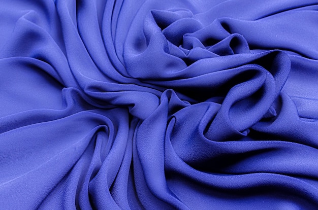 Close-uptextuur van natuurlijke blauwe stof of doek in dezelfde kleur. Stoffentextuur van natuurlijk katoen of zijde of wol textielmateriaal. Blauwe canvasachtergrond.
