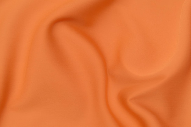 Close-uptextuur van natuurlijke rode of roze of oranje stof of doek in dezelfde kleur. Stoffentextuur van natuurlijk katoen, zijde of wol, of linnen textielmateriaal. Rode en oranje canvasachtergrond.