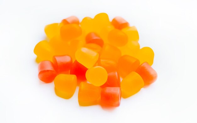 Foto close-uptextuur van oranje en gele multivitaminegummies in de vorm van beren op witte achtergrond