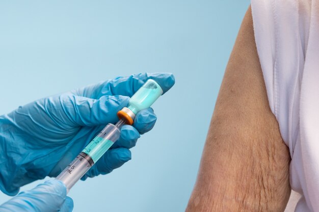 Close-upverpleegster die vaccininjectie doet aan hogere vrouw.