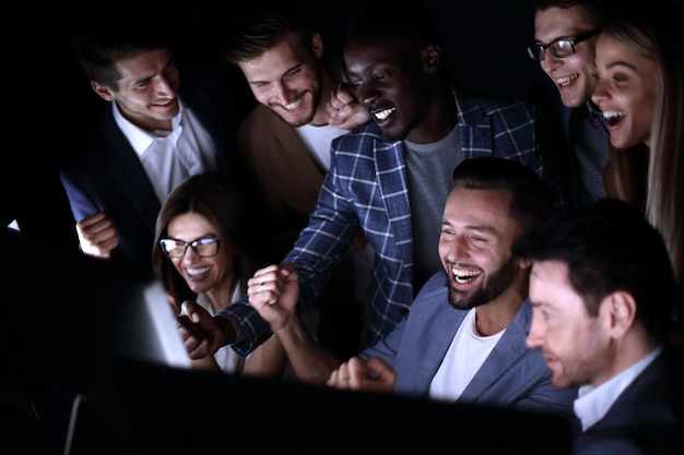 Close-upVrolijke zakenmensen kijken naar het computerscherm online overwinning