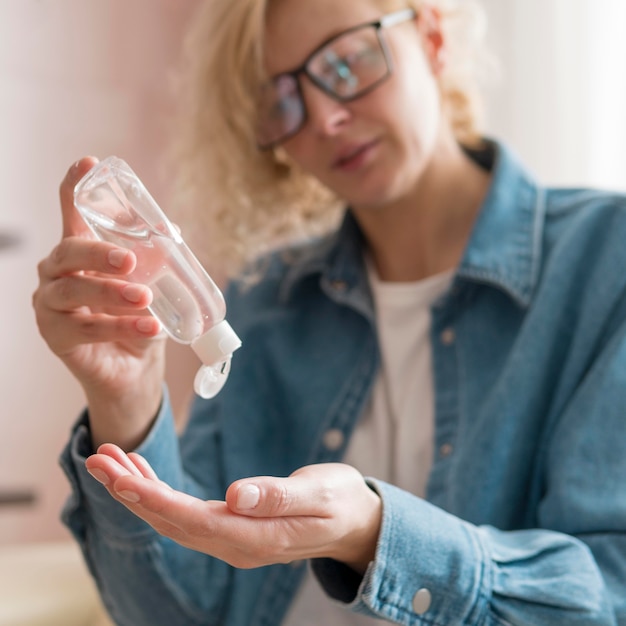 Close-upvrouw die handdesinfecterend middel gebruiken