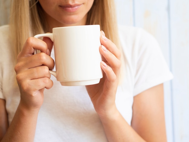 Close-upvrouw die witte mok steunen