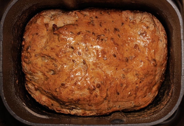 Close-upweergave van tarwebrood met gouden korst met zaden in een metalen broodbakmachine