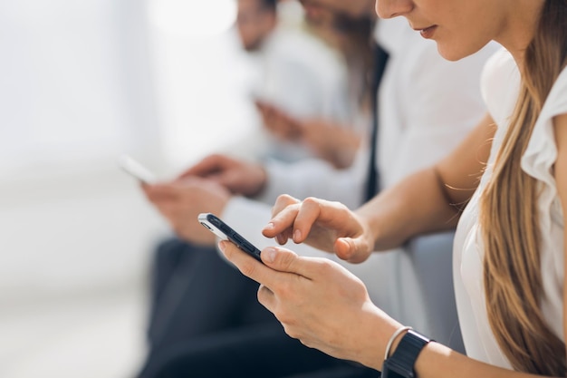 Primo piano giovane donna d'affari con smartphone su sfondo sfocato dell'ufficio