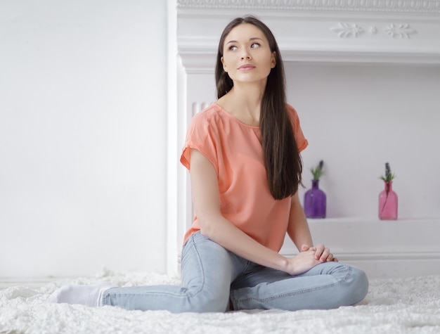 Close upyoung woman sitting on white carpet in living room