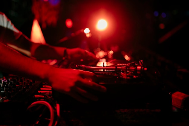 Close view of the hands of a disc jockey mixing a vinyl records during a performs in a music festiva