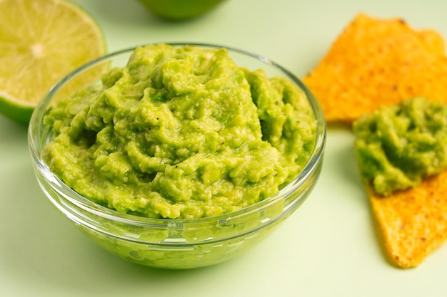 Close view of homemade mexican dipping sauce made of mashed avocado served in glass bowl with nacho