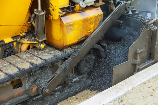 Close view the workers and the asphalting machines