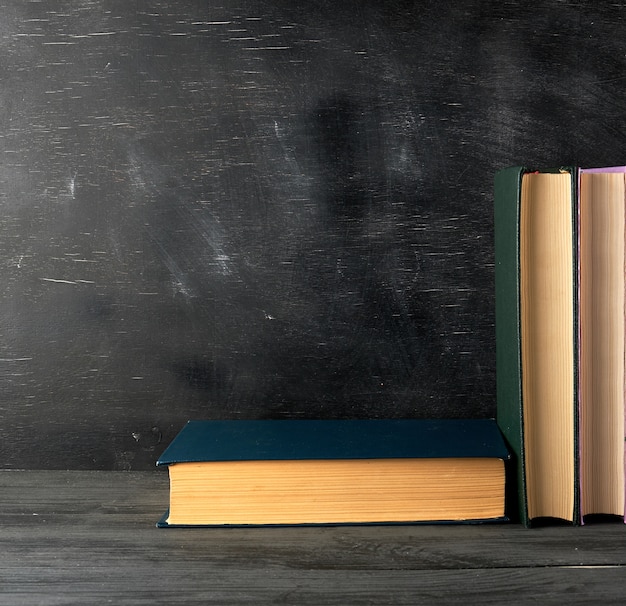 Closed books with yellow sheets on a black chalk board background