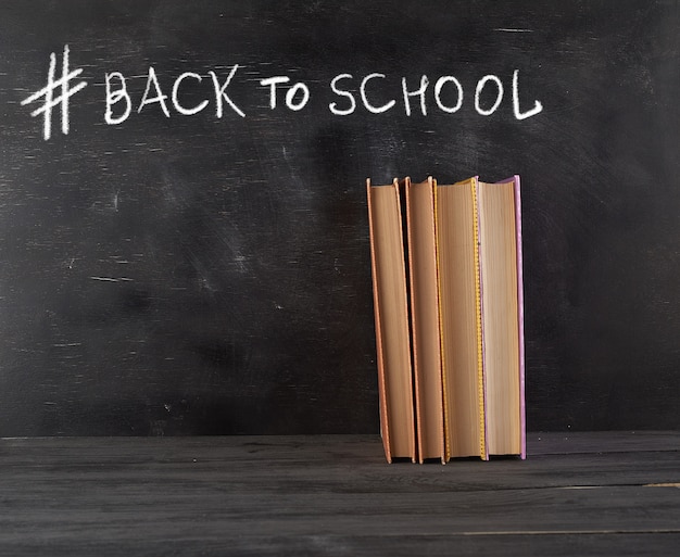 Closed books with yellow sheets on a black chalk board 