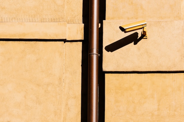 Closed circuit television (CCTV) camera on a yellow building wall. Security Concept.