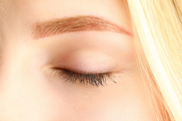 Closed eye of beautiful blonde woman in morning sunshine close-up